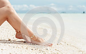 Women`s sexy legs on the beach, the concept of beach summer vacation
