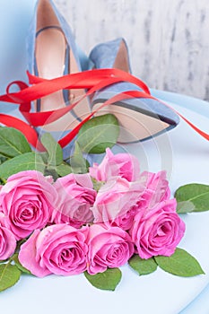 Women`s shoes blue high-heeled. Elegant shoes and a bouquet of roses in the interior. A gift for a girl in the feast of women.