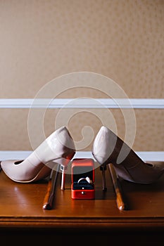 Women`s shoes and wedding rings in a box on a wooden tabletop