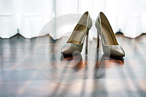 The women`s shoes on the wooden floor with shadow on the floor, the sun light behind the white curtain - low angle