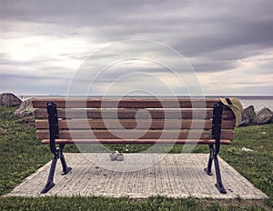 Women`s straw hat hanging on wooden park bench and shoes beside it