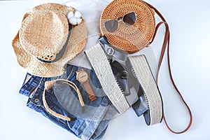 Women`s summer clothes collage on white, flat lay. Woven sandals, rattan bag, hat, watch, shorts, sunglasses top view