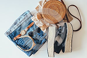 Women`s summer clothes collage on white, flat lay. Woven sandals, rattan bag, hat, watch, shorts, sunglasses top view