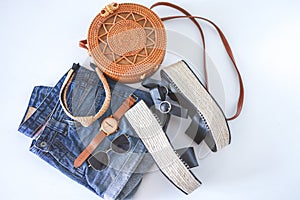 Women`s summer clothes collage on white, flat lay. Woven sandals, rattan bag, watch, shorts, sunglasses top view