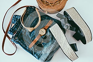 Women`s summer clothes collage on white, flat lay. Woven sandals, rattan bag, watch, shorts, sunglasses top view