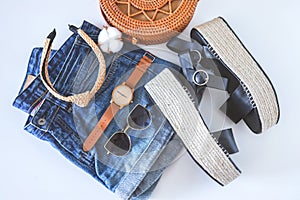 Women`s summer clothes collage on white, flat lay. Woven sandals, rattan bag, watch, shorts, sunglasses top view