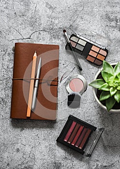 Women`s table with work organizer, cosmetic, pens, succulent flower on a grey table, top view. Flat lay beautiful female still