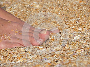 Women`s tanned legs on the sea sand