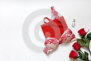 Women`s underwear and red roses on white surface. Red lacy lingerie on white background. Concept of love. Flat lay.
