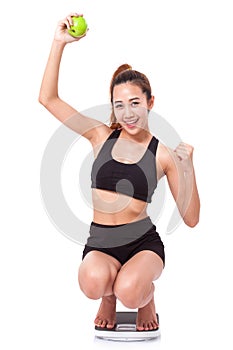 Women on scale cheering for achieving her weight loss goal