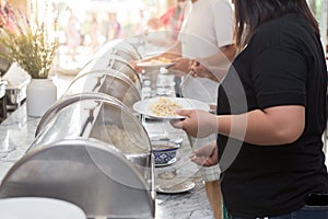 Women are scooping food from chafing dishes on the table at the  luxury banquet