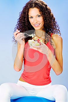 Women seating on blue pilates ball holding fresh salad on plate