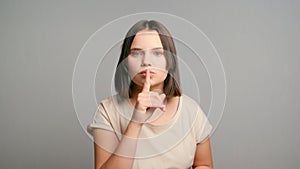 Women secrets. Latin teen girl showing secret sign. Young female with finger near lips. Closeup portrait of young woman