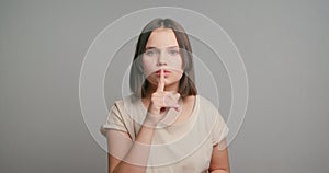 Women secrets. Latin teen girl showing secret sign. Young female with finger near lips. Closeup portrait of young woman