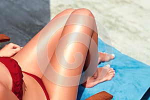 Women sexy legs on the beach. Skincare. Sun protection  on her smooth tanned legs.