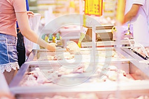 Women shoping Fresh food on the market today is chicken wings meat in a store