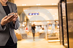 Women in shopping mall using mobile phone.