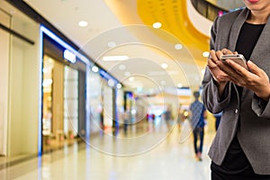 Women in shopping mall using mobile phone.