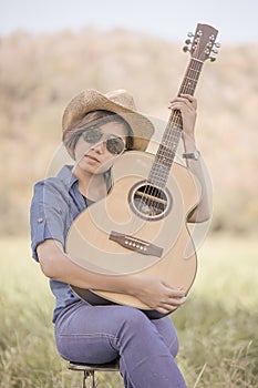 Women short hair wear hat and sunglasses sit playing guitar in g