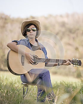 Women short hair wear hat and sunglasses sit playing guitar in g