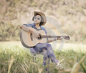 Women short hair wear hat and sunglasses sit playing guitar in g