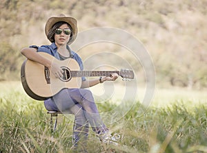 Women short hair wear hat and sunglasses sit playing guitar in g