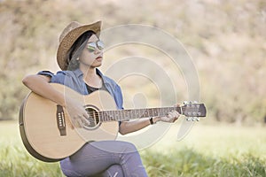 Women short hair wear hat and sunglasses sit playing guitar in g