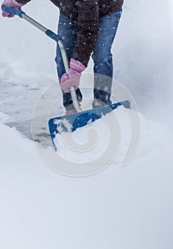 Women shoveling snow wearing fuzzy pink gloves during a storm