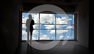 Women silhouette beside the big window and sky