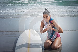 women sitting on the beach she has a hartache from heart attack after working out by surfing in the sea