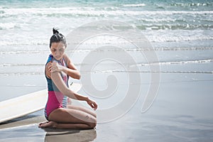 women sitting on the beach she has a shoulder injury after working out by surfing in the sea