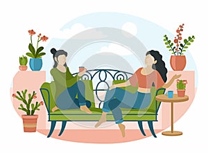 Women sitting on decorative sofa in interior indoor plants. Two girls drinking tea and talking in relaxing environment