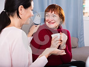 Women sitting together with cup of tea at sofa