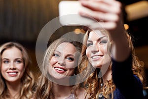 Women with smartphone taking selfie at night club