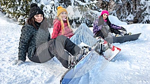 Women snowboarders sitting on the snow