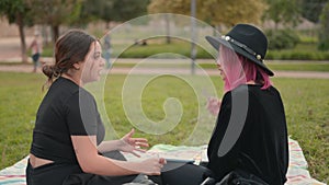 women spending leisure time and chatting while sitting at city park. push in slomo shot