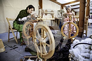 Women spinning thread with a wooden spinning wheel