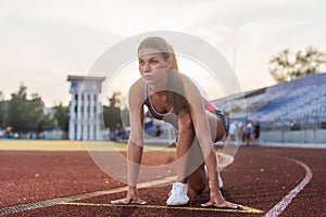 Women sprinters at starting position ready for race on racetrack.