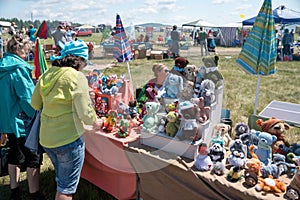 Women stand near the counter with crocheted toys at the Karatag festival of music and crafts.