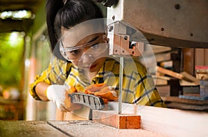 Women standing is craft working cut wood at a work bench with band saws power tools at carpenter machine in the workshop