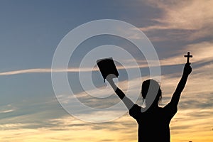 Women standing holding holy  bible for worshipping God at sunset background, Pray to the god, christian silhouette concept