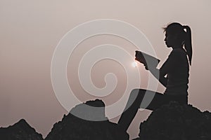Women standing holding holy bible for worshipping God at sunset background, Pray to the god, christian silhouette concept
