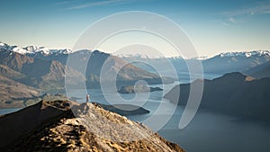 Women standing on the mountain summit enjoying the view on lake and mountains during early morning