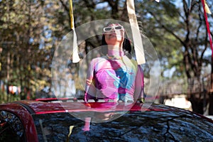 Women standing out of car sunroof in summer road trip