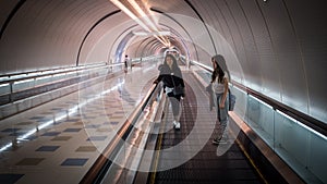 Women standing in tunnel on escalator