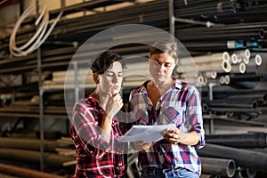 Women standing in warehouse and talking about documentation