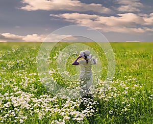 Women in straw hat and white dress relaxing on green wild  flield with flowers  under blue sky nature landscape