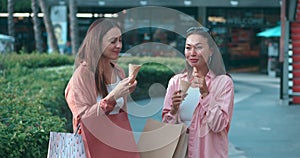 Women on street eating ice cream their faces lit with pleasure from cold food. Pleasure from ice cream brings smiles joy