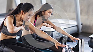 women stretch hands to legs in gym