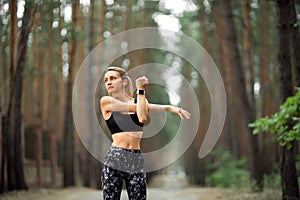 Women stretching arms and breathing fresh air in middle of pinewood forest while exercising. Workouts and Lifestyles